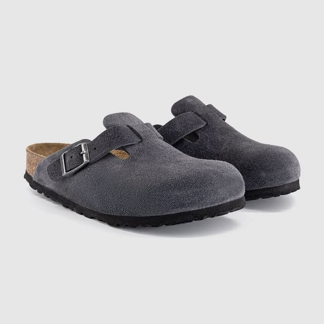 Pair of gray suede clogs with a buckle on a light gray background
