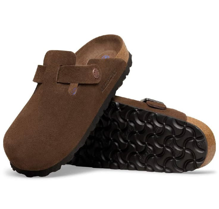 Brown suede clogs with black soles on a white background