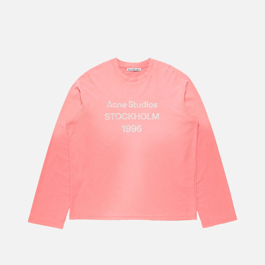 A coral pink long-sleeve t-shirt with white text reading 'Acne Studios STOCKHOLM 1995' printed on the chest, displayed flat against a light gray background.