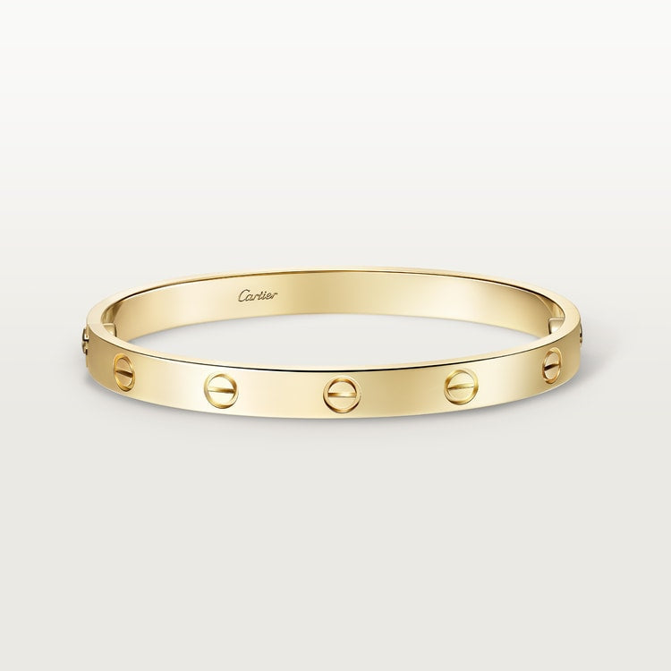 Gold bracelet with Cartier logo on a light gray background