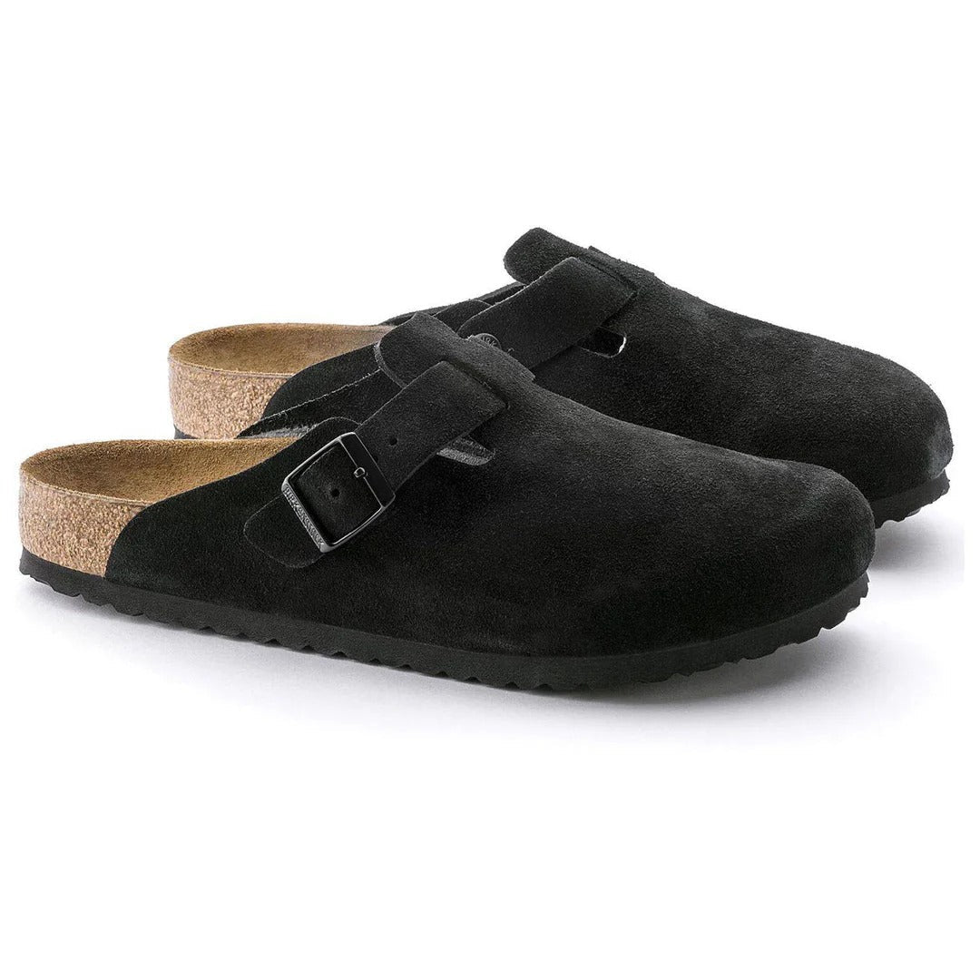 Pair of black suede clogs with cork insole on a white background