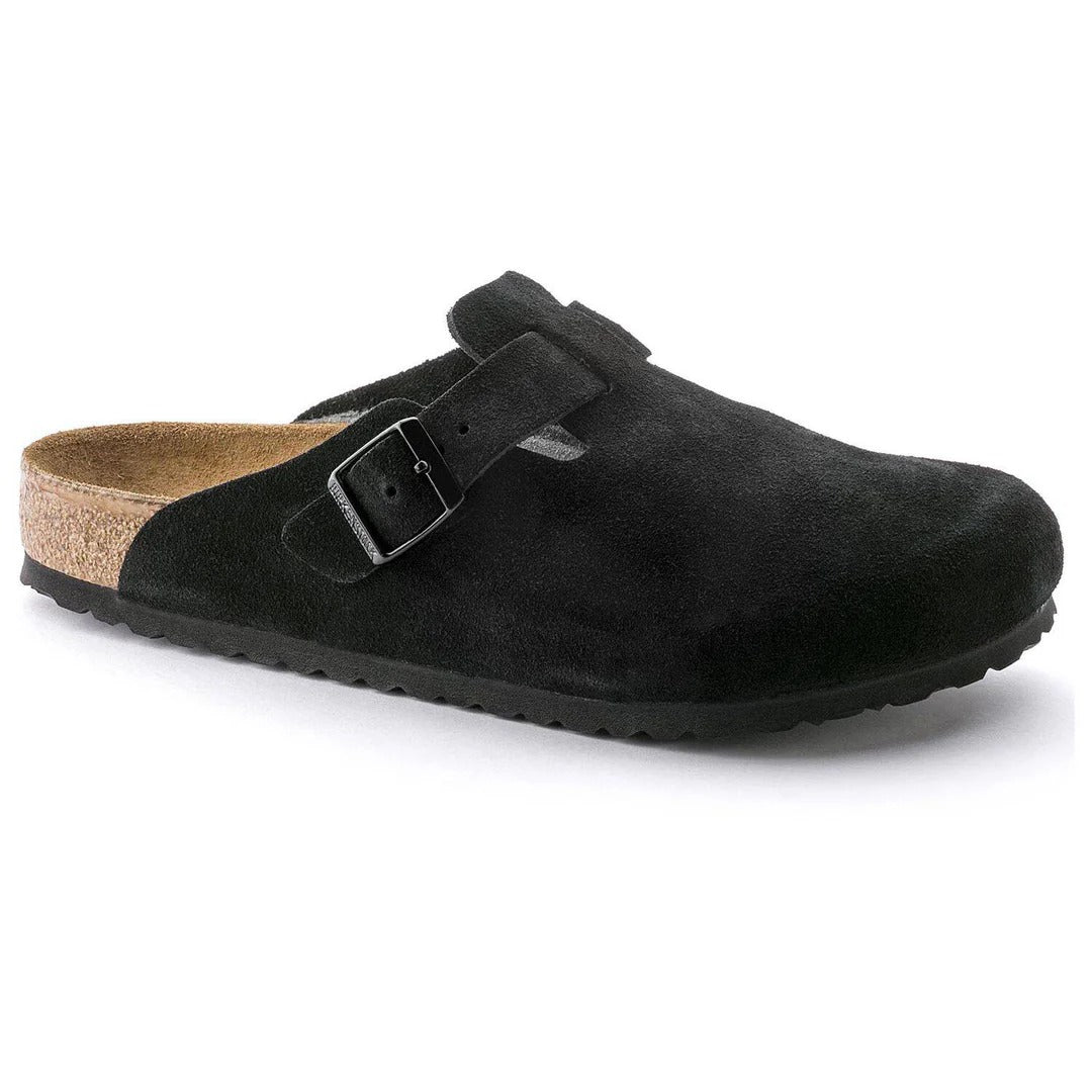 Black suede clog shoe with a buckle on a white background