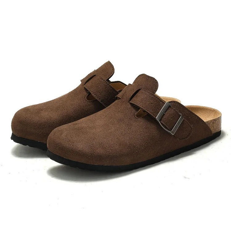 Pair of brown suede clogs with buckles on a white background